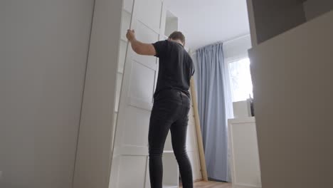 Man-assembling-white-closet-in-new-apartment-in-slow-motion,-stable-shot