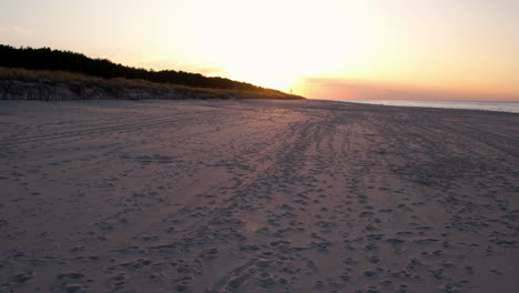 POV-of-beautiful-sunset-sandy-beach-with-animal-footprint-tracks-and-trails