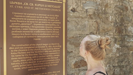 Young-female-tourist-reads-foreign-visitor-info-board-Cyrillic-translation