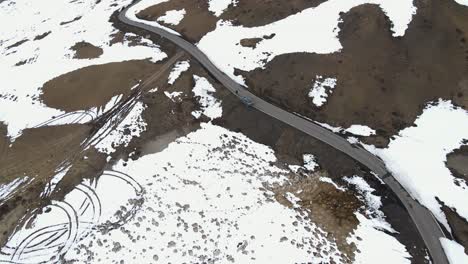 aerial-view-of-snowy-ice-high-mountains-road-with-car-driving-on-world's-highest-village-hikkim-in-spiti-valley-in-himachal-pradesh