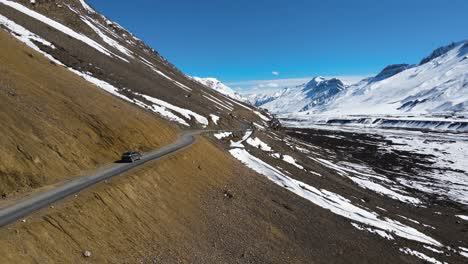 Drone-Siguiendo-Un-Jeep-Todoterreno-Conduciendo-En-Kaza-En-El-Valle-De-Spiti-En-El-Himalaya-India-Asia-Explorando-El-Destino-De-Viaje