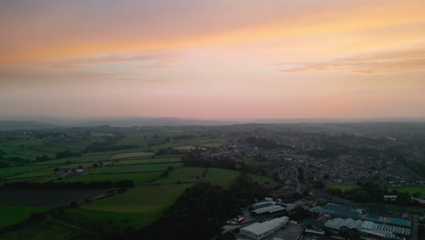Experience-Heckmondwike,-UK,-through-captivating-drone-shot-aerial-footage,-highlighting-industrial-structures,-lively-streets,-and-the-historic-town-center-during-a-summer-evening