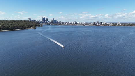 Speed-boat-cruising-past-drone-on-the-Swan-river-in-Perth,-Western-Australia-on-clear-sky-day