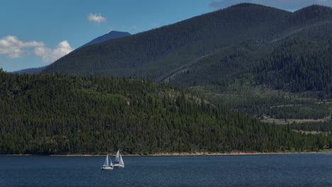 Aerial-cinematic-drone-zoom-two-sailboats-sailing-Lake-Dillon-Colorado-Swam-mountain-summer-blue-sky-beautiful-daytime-Frisco-Silverthorne-Reservoir-marina-Breckenridge-Keystone-follow-left-movement