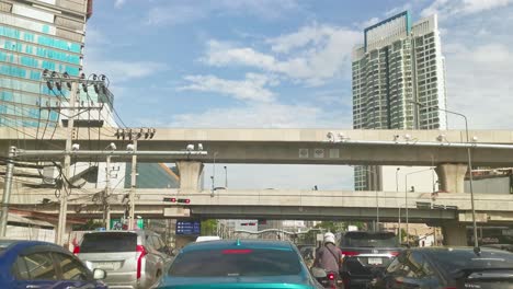 Beautiful-Day-with-a-BTS-Skytrain-Line-Crossing-Over-at-an-Intersection-While-Waiting-in-Traffic-at-Ratchayothin,-Bangkok,-Thailand