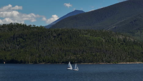 Aerial-cinematic-drone-zoom-two-sailboats-sailing-Lake-Dillon-Colorado-Swam-mountain-summer-blue-sky-beautiful-daytime-Frisco-Silverthorne-Reservoir-marina-Breckenridge-Keystone-follow-right-circle