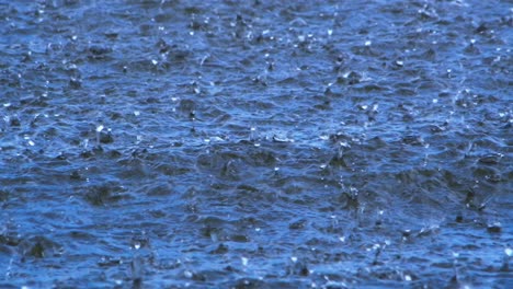 Big-rain-on-the-water-surface,-the-water-is-blue,-the-drops-splash