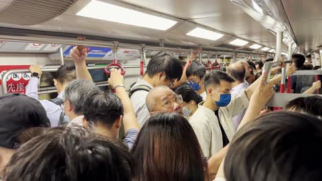 Zeitlupe-Im-überfüllten-Hongkonger-MTR-Zug-Mit-Maskierten-Pendlern-Während-Der-Hauptverkehrszeit