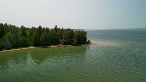 Aerial-flyover-forest-trees-lake-Huron,-Michigan