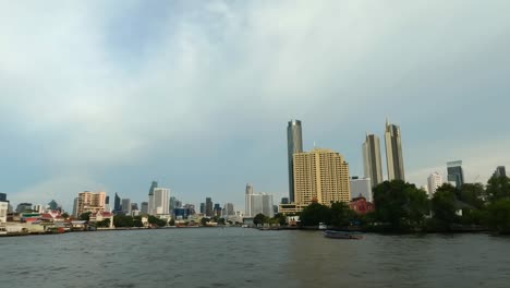 Pov-shot-from-boat-during-boat-tour-on-Chao-Phraya-River-in-Bangkok-City-during-cloudy-day,-Thailand