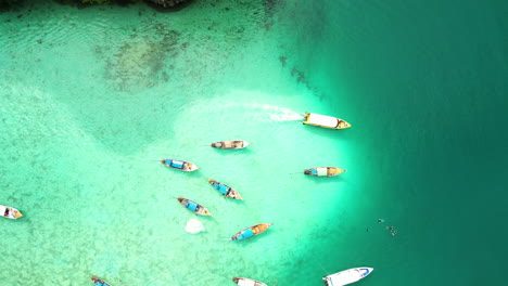 Various-asian-traditional-boats-sailing-the-turquoise-shallow-waters-of-coral-reef,-Southeast-Asia