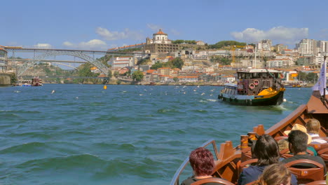 Schlepper,-Gefolgt-Von-Einem-Touristenboot,-Das-über-Den-Fluss-Douro-Mit-Der-Brücke-Dom-Luís-I-In-Porto,-Portugal,-Segelt