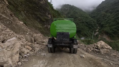 Driving-on-a-rugged-mountain-road-in-Nepal-following-a-green-water-truck