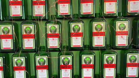 Jägermeister-Alcohol-Digestivo-Alemán-Botellas-Verdes-En-Una-Pared,-Bebida-Alcohólica,-Toma-De-4k