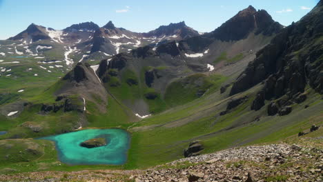 Aerial-cinematic-upper-view-Ice-Lake-Basin-Silverton-Island-Lake-aqua-blue-clear-water-alpine-tundra-stunning-mountain-range-snow-wildflowers-mid-summer-daytime-beautiful-slow-pan-to-the-left-motion