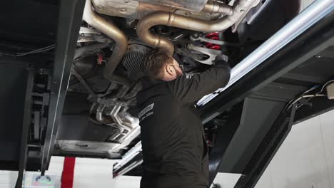 Garage-mechanic-examining-under-the-car-at-repair-shop
