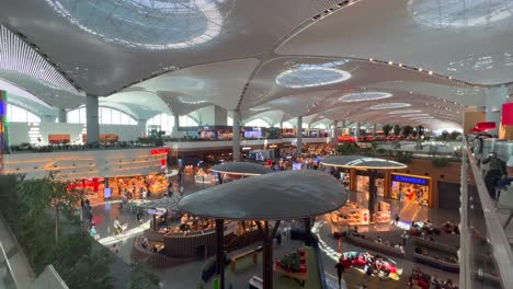 Amazing-view-from-Turkish-Airlines-business-lounge-onto-international-airport-in-Istanbul,-people-walking-around-shops-and-restaurants-in-Turkey,-busy-airport-with-luxury-stores,-4K-shot