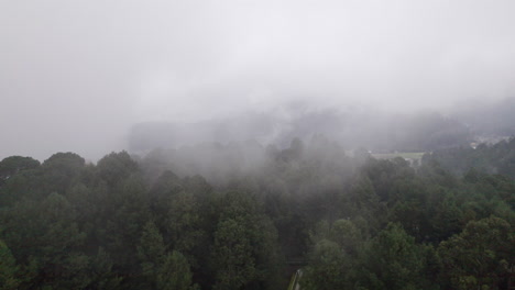 Aerial-Flight-through-clouds-and-mist-over-tall-trees-in-a-gloomy,-rainy-day-in-Valle-De-Bravo,-Mexico