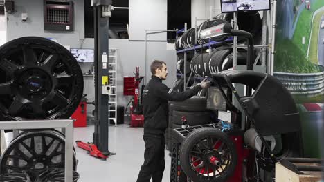 Tire-workshop-technician-using-auto-wheel-balancer-machine-to-repair-wheel