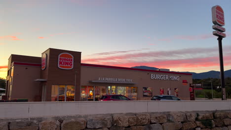 Beautiful-pink-orange-sunset-at-Burger-King-restaurant-in-Estepona-Spain,-amazing-sunset-at-Auto-King-drive-through,-4K-panning-right