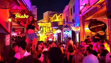 Hot-girl-table-dancing-at-a-famous-popular-party-street-in-Bodrum-Turkey-holiday,-fun-summer-nights-on-vacation,-4K-shot