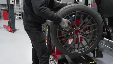 Tire-workshop-technician-setting-up-car-wheel-for-auto-wheel-balancing-diagnosis