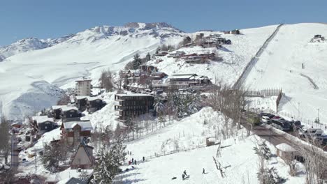 Aerial-view-of-People-playing-in-snow-Hillside-at-Farellones-snow-resort,-Ascending-shot