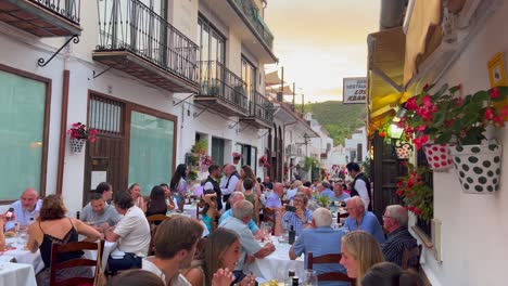 People-sitting-and-having-dinner-outside-in-Los-Abanicos-restaurant-in-Benahavis-Spain,-romantic-street-in-the-evening-during-summer,-4K-shot