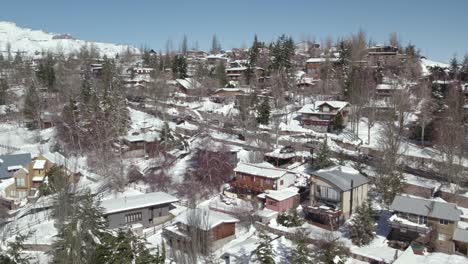 Flyover-a-picturesque-mountain-town,-wood-and-stone-houses-covered-in-Snow,-Farellones