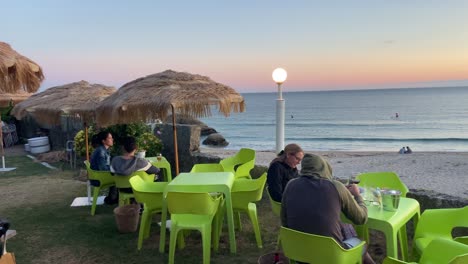 Restaurante-De-Playa-Paraíso-Tropical-Junto-Al-Mar-Con-Turistas-Al-Atardecer