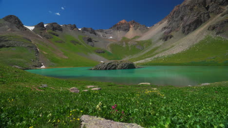 Colorado-Ice-Lake-Basin-trailhead-lower-incredible-bright-blue-alpine-clear-water-summer-wildflowers-blue-sky-Rocky-Mountain-snow-range-peaks-Silverton-Telluride-dreamy-peaceful-slow-pan-left-motion