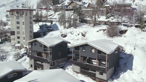 Close-up-aerial-view-of-cabins-under-construction-in-the-snowy-mountain-village-of-Farellones,-wood-and-stone-construction-of-the-area,-Chile