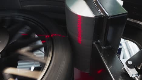 Car-wheel-getting-diagnosed-by-auto-wheel-balancer-machine,-Closeup