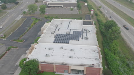 solar-panels-at-the-rooftop-of-building,-aerial-jib-shot
