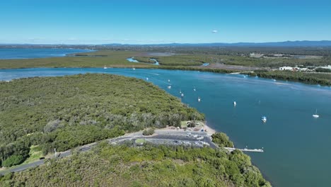 Aerial-drone-shot-orbiting-Beachmere-Boat-Ramps-on-Caboolture-River,-Boats-in-river-opening-to-the-Ocean-Moreton-Bay