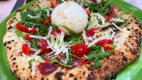 Traditional-Italian-pizza-with-burrata-cheese,-tomatoes,-rocket-salad-and-parma-ham,-tasty-food,-4K-shot