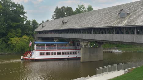 Ein-Touristenboot-Fährt-An-Einem-Spätsommertag-Unter-Der-überdachten-Brücke-Des-Bayerischen-Gasthauses-Holzbrücke-Auf-Dem-Cass-River-Hindurch