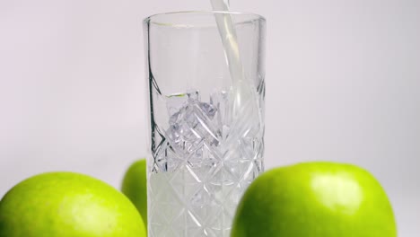 Static-slow-motion-shot-from-a-nice-glass-which-is-filled-with-a-delicious-green-apple-whey-shake-before-the-workout-or-workout-with-surrounding-fresh-green-apples
