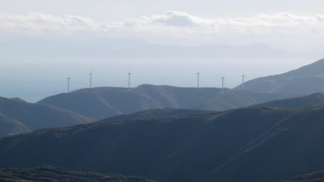 Eine-Gruppe-Von-Windkraftanlagen-Auf-Einem-Hügel-Mit-Blick-Auf-Den-Ozean
