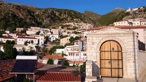 Touristic-village-of-Dhermi-in-Albanian-coastline-of-Ionian-sea,-stone-houses-with-red-roofs-on-rocky-hills-at-morning-sunshine