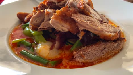 Traditional-Thai-red-curry-crispy-duck-dish-with-vegetables,-authentic-Thai-cuisine-restaurant,-4K-shot