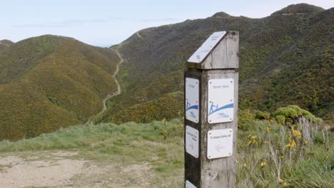 A-sign-showing-directions-on-a-walking-track-with-hills-in-the-background