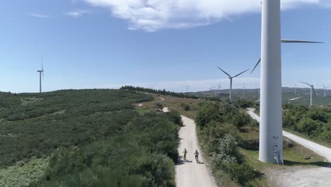 Zwei-Radfahrer-Auf-Der-Straße-Mit-Windmühlen
