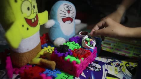 Kinderhände-Spielen-Mit-Lustigen-Bauklötzen,-SpongeBob-Puppen-Und-Doraemon-Puppen,-Sie-Sind-Glücklich-Und-Glücklich