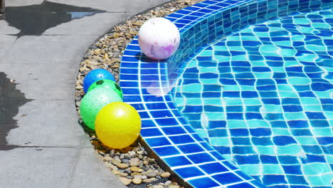 Colorful-beach-ball-on-edge-and-floating-in-pool