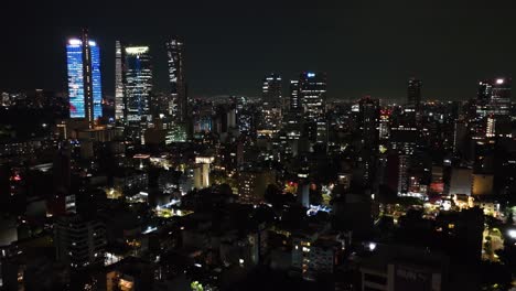 Aerial-view-ascending-in-front-of-the-night-lit-skyline-of-Mexico-city