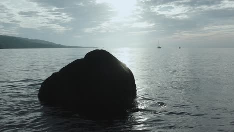 Aufnahme-Eines-Felsens-Im-Ozean,-Der-Sich-Vor-Der-Morgensonne-Abzeichnet