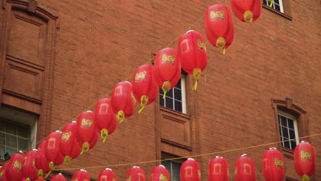 China-Town-Feiert-Das-Neue-Chinesische-Jahr-In-London,-Leicester-Street-Hängt-An-Vielen-Schnüren,-Viele-Traditionelle-Laternenballons-Ziehen-Sich-An-Fenstern-Fest,-Windiges-Wetter,-Das-Sich-Bewegt,-Bewölktes-Wetter