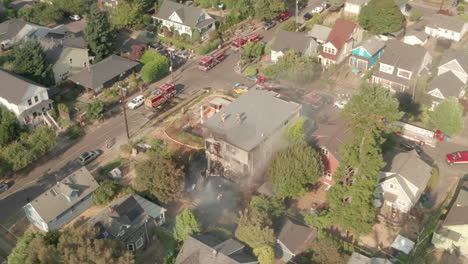 Pan-down-aerial-shot-of-fire-fighters-surrounding-a-burning-building