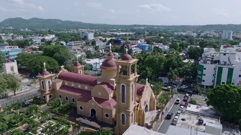 Ascending-aerial-shot-of-yellow-cathedral-with-red-roof-in-San-Cristobal-City-during-sunny-day---Backwards-flight